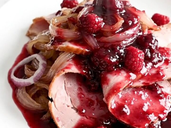 A spiral-sliced ham in a slow cooker topped with raspberry preserves and smoky chili powder.