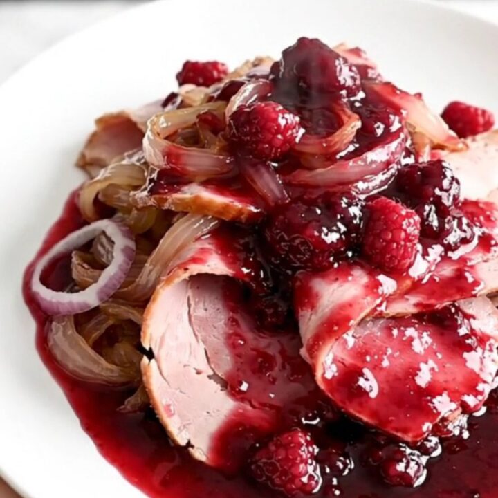 A spiral-sliced ham in a slow cooker topped with raspberry preserves and smoky chili powder.