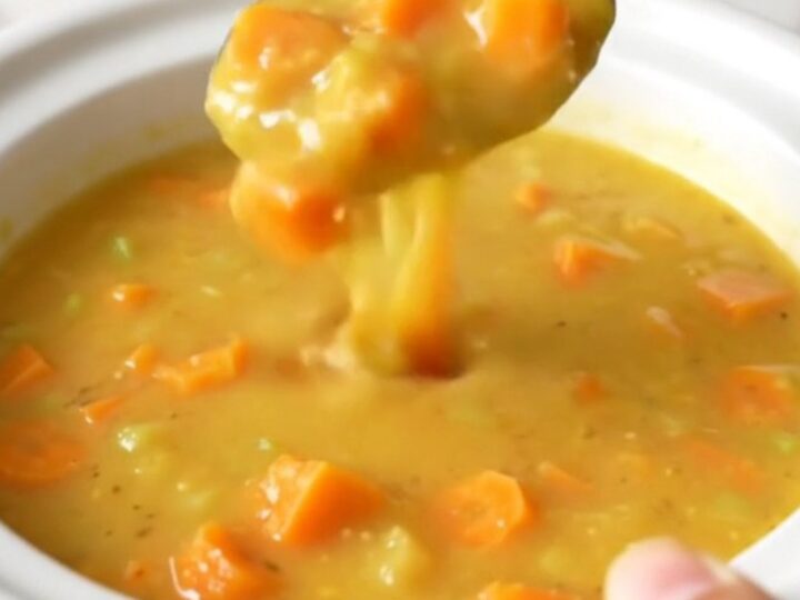 A slow cooker filled with creamy Wisconsin beer cheese soup featuring visible carrot and onion pieces.