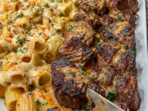 A close-up of tender Cajun-spiced steak bites served with creamy Parmesan rigatoni on a white platter.