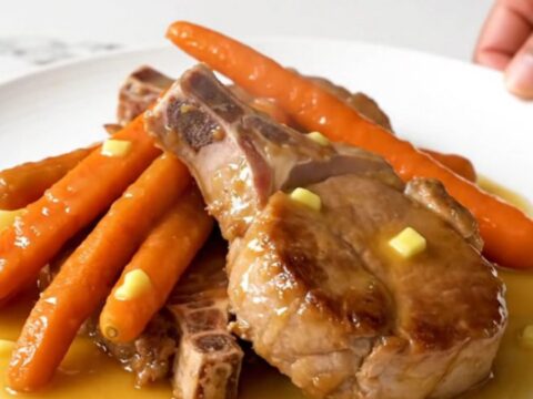Close-up of tender slow-cooked pork chops and baby carrots glazed in a glossy honey butter sauce.
