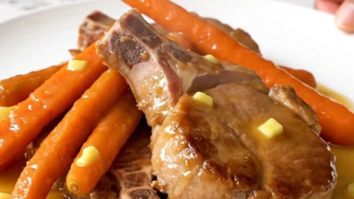 Close-up of tender slow-cooked pork chops and baby carrots glazed in a glossy honey butter sauce.