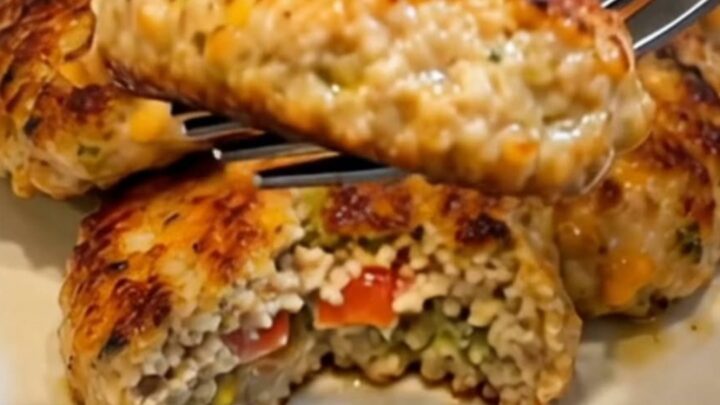 A close-up of a crispy, golden-brown chicken patty with melted cheese and corn visible inside.