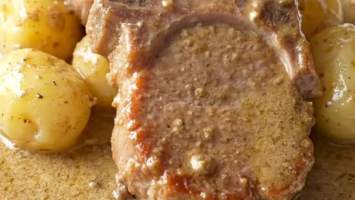 A close-up of tender, slow-cooked pork chops covered in a rich, creamy mushroom gravy with soft baby potatoes.