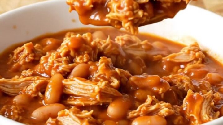 A stainless steel slow cooker filled with a rich, saucy mixture of ground turkey and mixed beans.
