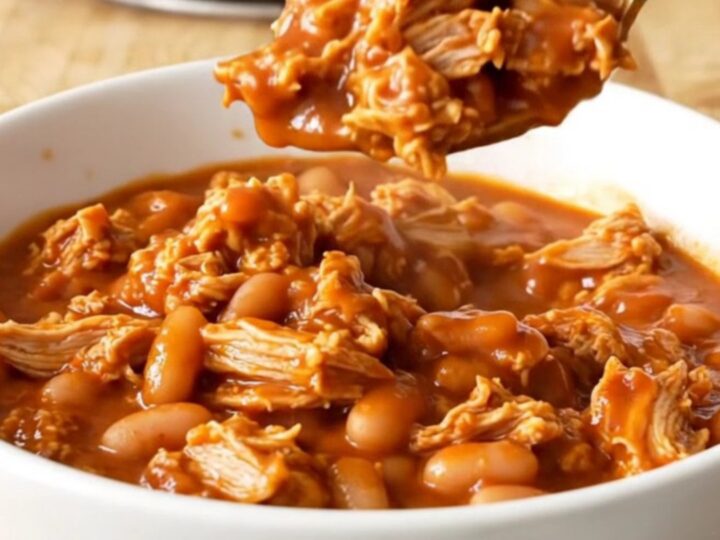A stainless steel slow cooker filled with a rich, saucy mixture of ground turkey and mixed beans.