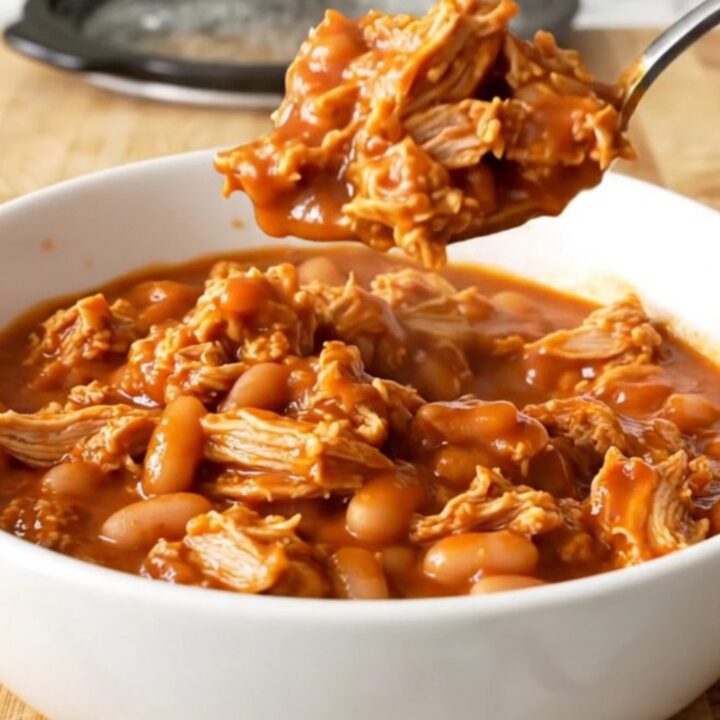 A stainless steel slow cooker filled with a rich, saucy mixture of ground turkey and mixed beans.