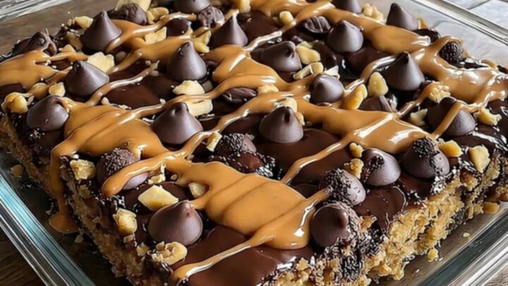 A warm, decadent peanut butter cup dump cake in a rustic square dish with molten chocolate and peanut butter.