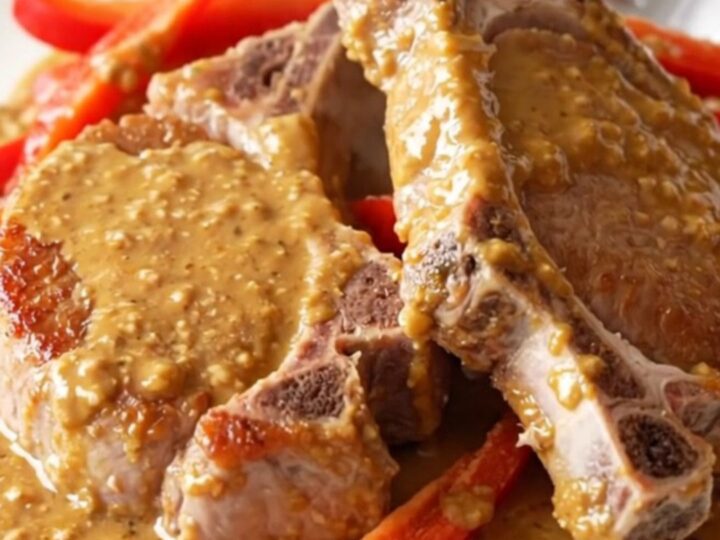 Slow cooker Thai peanut pork chops served on a plate with vibrant red bell pepper strips and a creamy sauce.