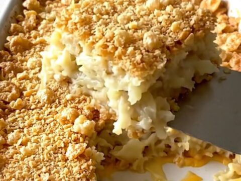A golden, crunchy-topped funeral potato casserole in a ceramic dish, ready to be served.