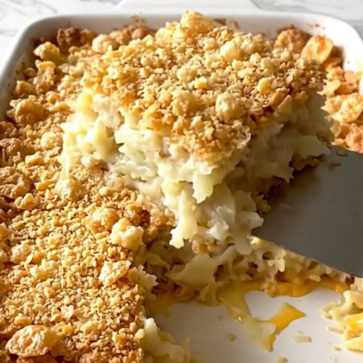 A golden, crunchy-topped funeral potato casserole in a ceramic dish, ready to be served.