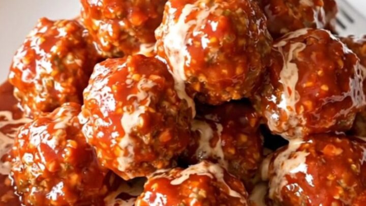 A slow cooker filled with turkey meatballs coated in a glossy, creamy pepper jelly sauce.