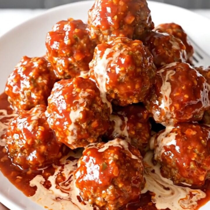 A slow cooker filled with turkey meatballs coated in a glossy, creamy pepper jelly sauce.