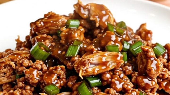 A top-down view of General Tso ground turkey in a slow cooker with vibrant green onions and a dark, glossy sauce.