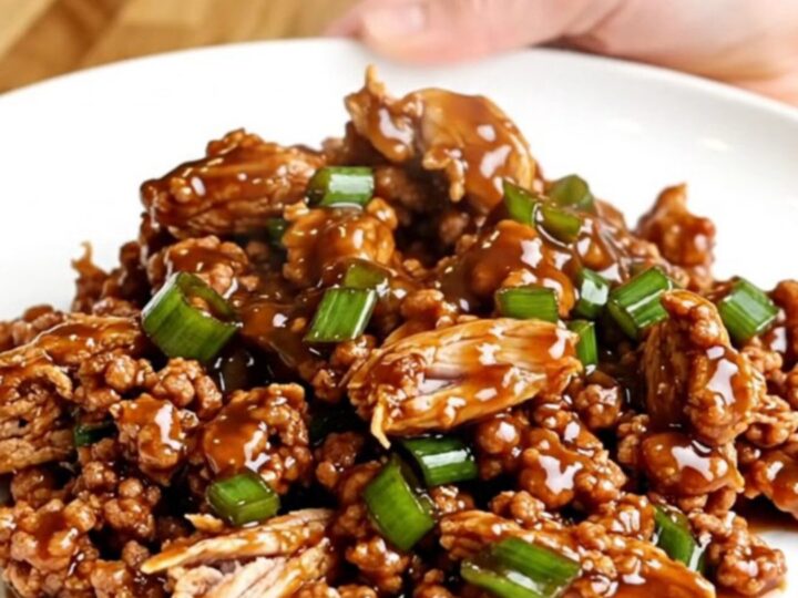 A top-down view of General Tso ground turkey in a slow cooker with vibrant green onions and a dark, glossy sauce.