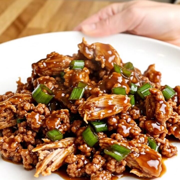 A top-down view of General Tso ground turkey in a slow cooker with vibrant green onions and a dark, glossy sauce.