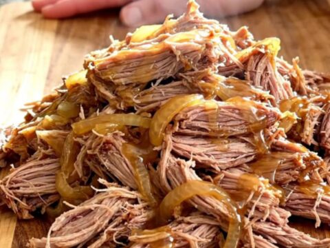 A slow cooker filled with tender pulled pork, caramelized onions, and a glossy hot honey glaze.