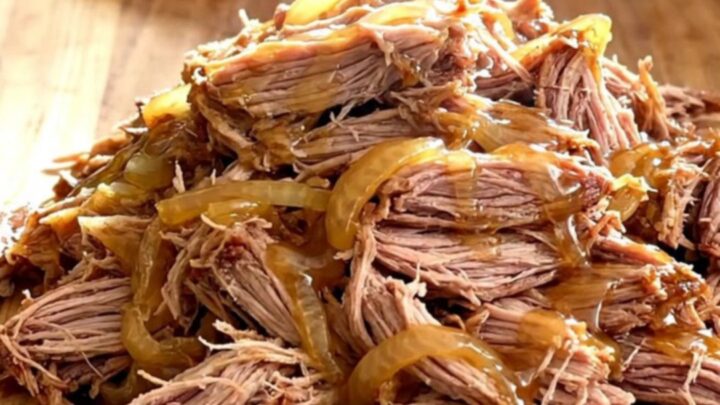 A slow cooker filled with tender pulled pork, caramelized onions, and a glossy hot honey glaze.