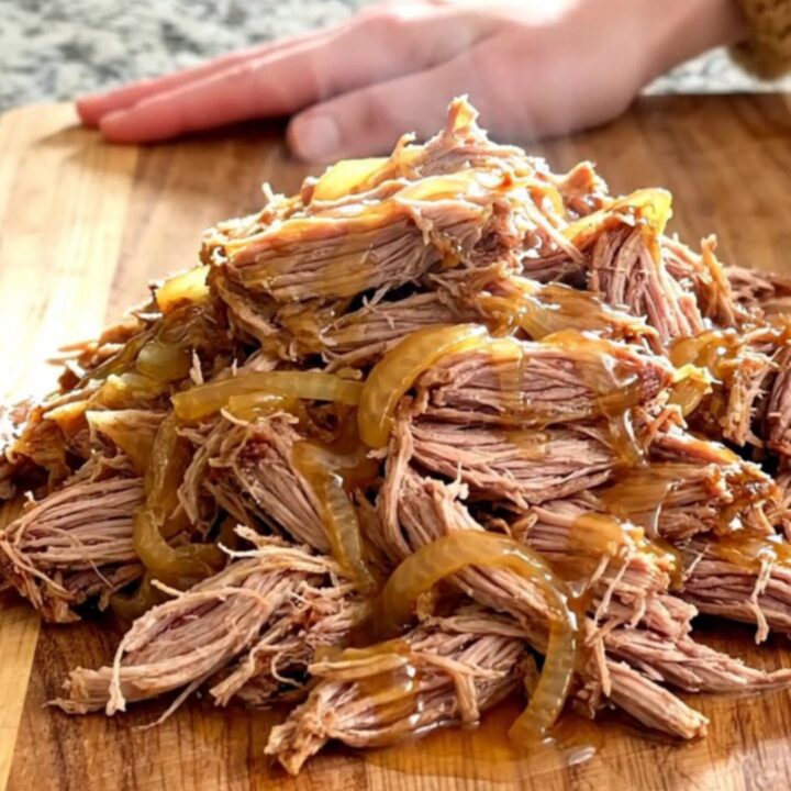 A slow cooker filled with tender pulled pork, caramelized onions, and a glossy hot honey glaze.