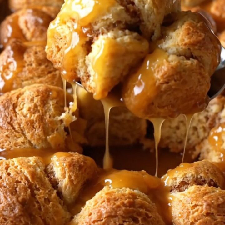A top-down view of raw biscuit dough pieces in a white dish, being drizzled with amber apple cider caramel sauce.