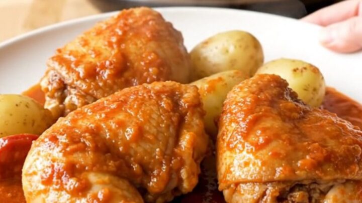 A stainless steel slow cooker filled with braised chicken thighs, chorizo coins