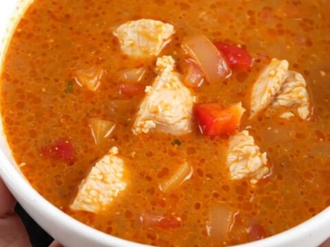 A creamy, vibrant red chicken paprikash soup in a slow cooker, featuring tender chicken and soft bell peppers.
