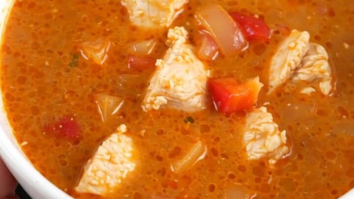 A creamy, vibrant red chicken paprikash soup in a slow cooker, featuring tender chicken and soft bell peppers.