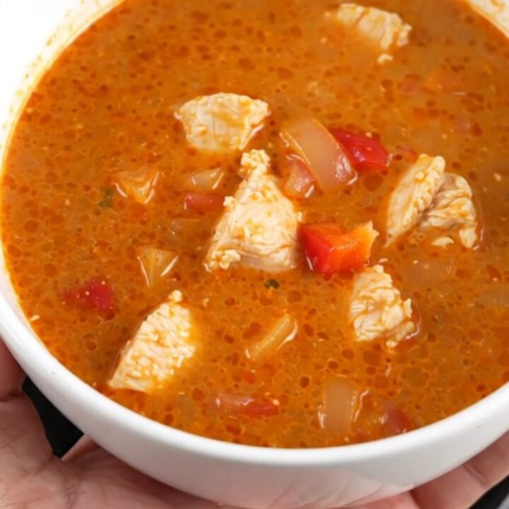 A creamy, vibrant red chicken paprikash soup in a slow cooker, featuring tender chicken and soft bell peppers.