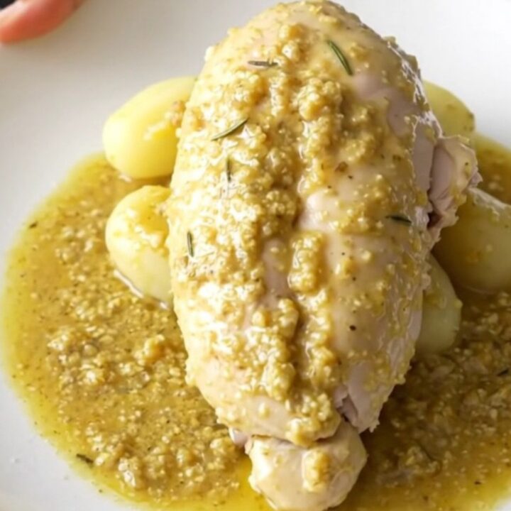 A close-up of tender braised chicken breast with soft baby potatoes in a creamy Dijon rosemary sauce.