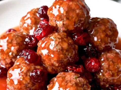 A slow cooker filled with turkey meatballs coated in a glossy, dark red cranberry orange sauce.