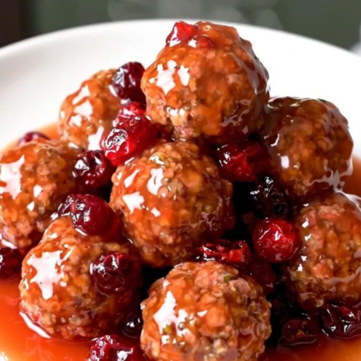 A slow cooker filled with turkey meatballs coated in a glossy, dark red cranberry orange sauce.
