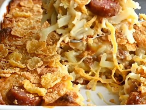 A golden-brown smoked sausage funeral potato casserole in a white baking dish.