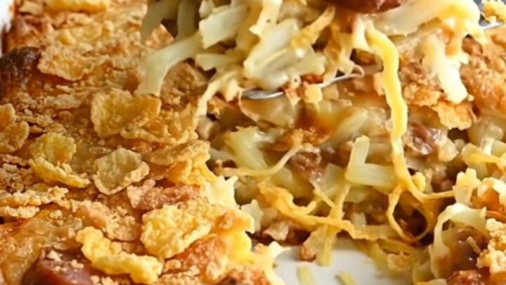 A golden-brown smoked sausage funeral potato casserole in a white baking dish.