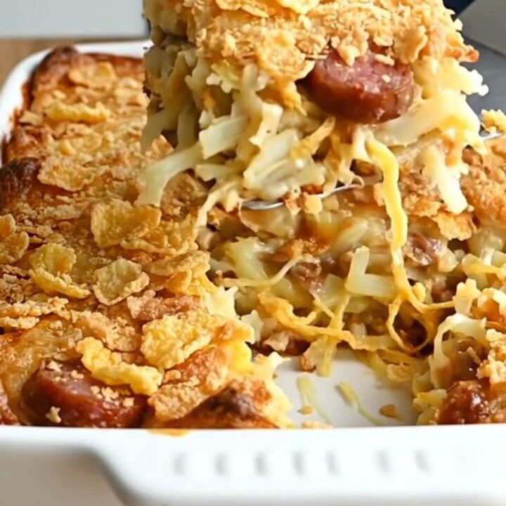 A golden-brown smoked sausage funeral potato casserole in a white baking dish.