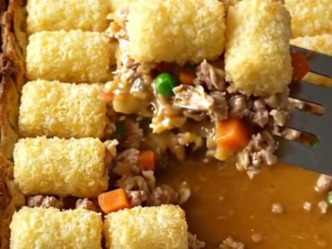 A top-down view of a rectangular baker filled with ground turkey, vegetables, and a golden layer of crispy potato tots.