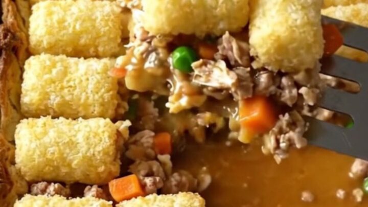 A top-down view of a rectangular baker filled with ground turkey, vegetables, and a golden layer of crispy potato tots.
