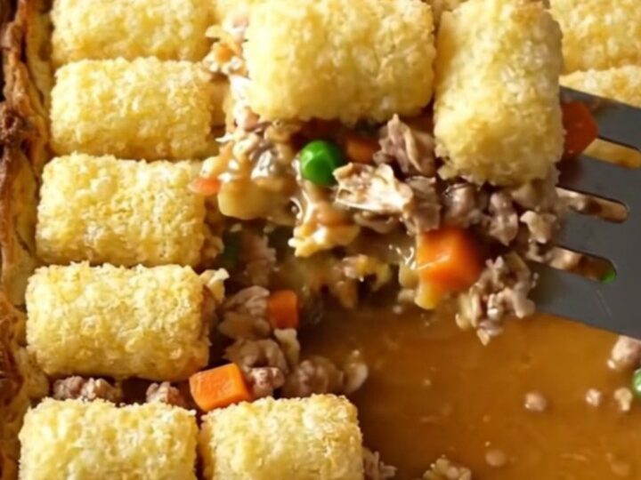 A top-down view of a rectangular baker filled with ground turkey, vegetables, and a golden layer of crispy potato tots.