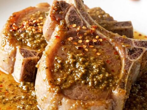 Bone-in pork chops braising in a rich, buttery herb sauce inside a slow cooker.