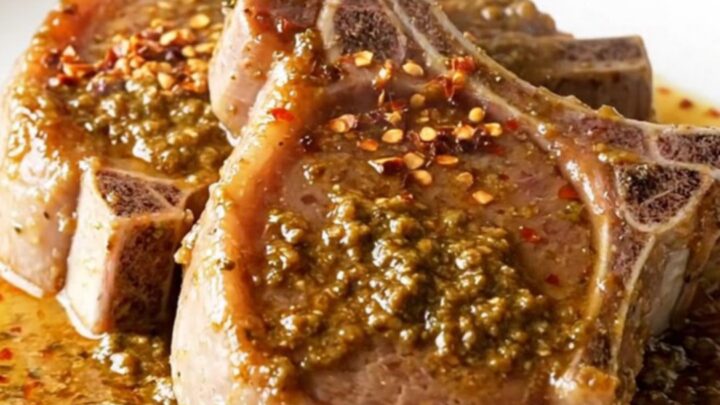 Bone-in pork chops braising in a rich, buttery herb sauce inside a slow cooker.