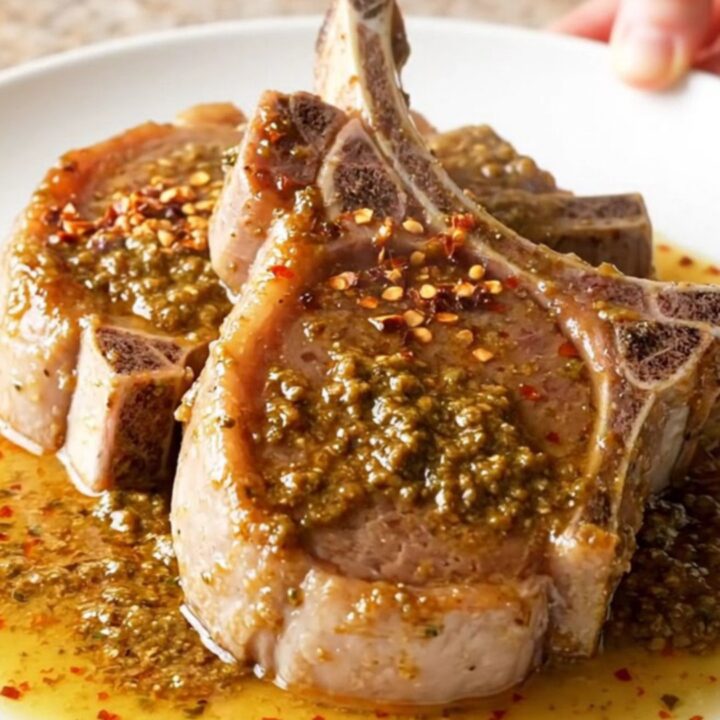 Bone-in pork chops braising in a rich, buttery herb sauce inside a slow cooker.