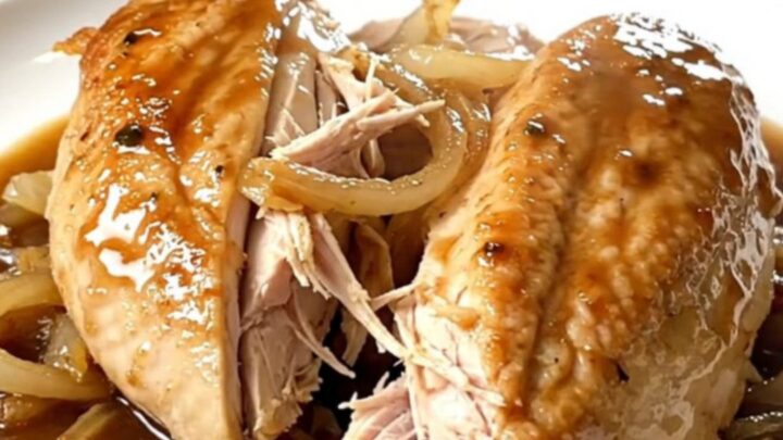 A close-up of tender, shredded chicken French dip served on a plate with savory au jus.