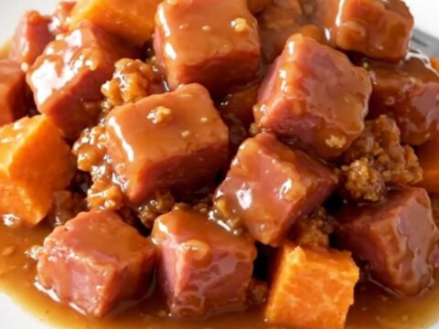 A close-up view of cooked ham cubes and soft sweet potato chunks in a rich