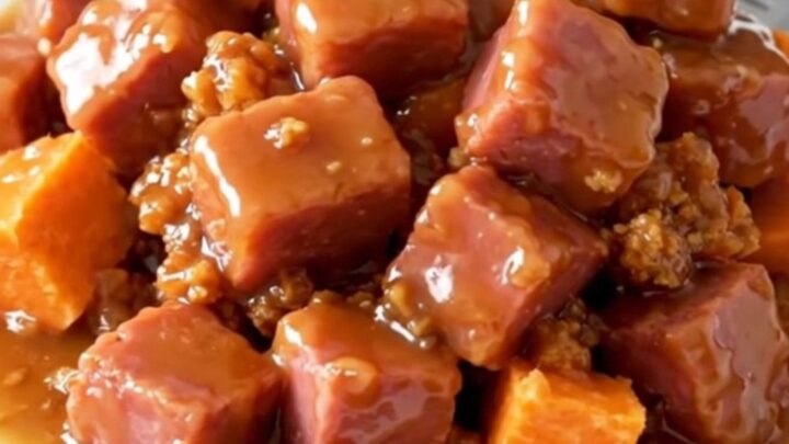 A close-up view of cooked ham cubes and soft sweet potato chunks in a rich