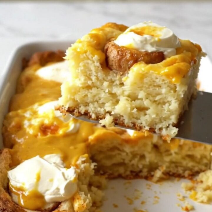 A rectangular ceramic dish filled with a golden-brown pumpkin cinnamon roll bake on a white countertop.