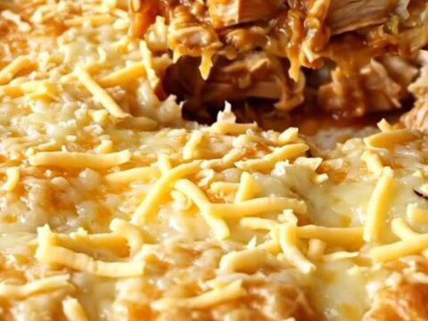 A golden, bubbly chicken enchilada bake in a ceramic dish, featuring puffed biscuits and melted cheese.