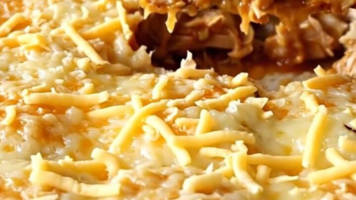 A golden, bubbly chicken enchilada bake in a ceramic dish, featuring puffed biscuits and melted cheese.