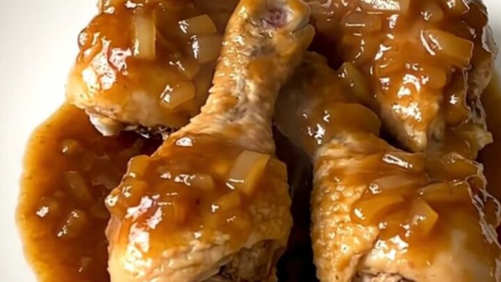 A plate of tender, slow-cooked chicken drumsticks coated in a glossy maple barbecue sauce with onions.