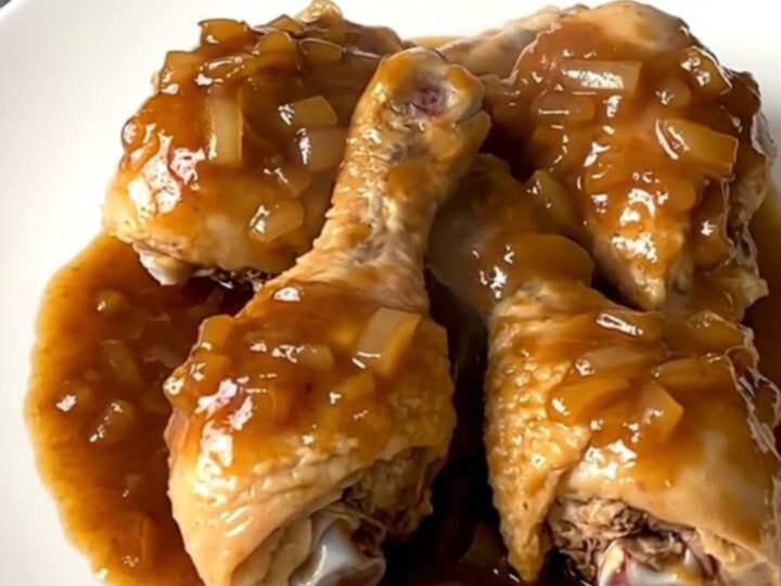 A plate of tender, slow-cooked chicken drumsticks coated in a glossy maple barbecue sauce with onions.