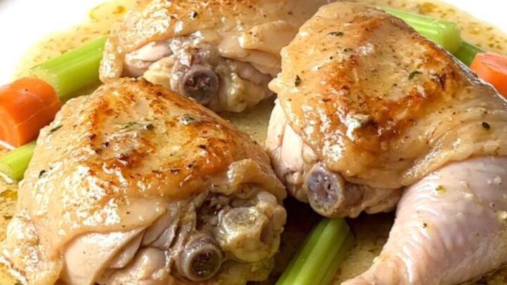 A close-up of a creamy chicken fricassee in a slow cooker with visible chicken thighs and carrots.