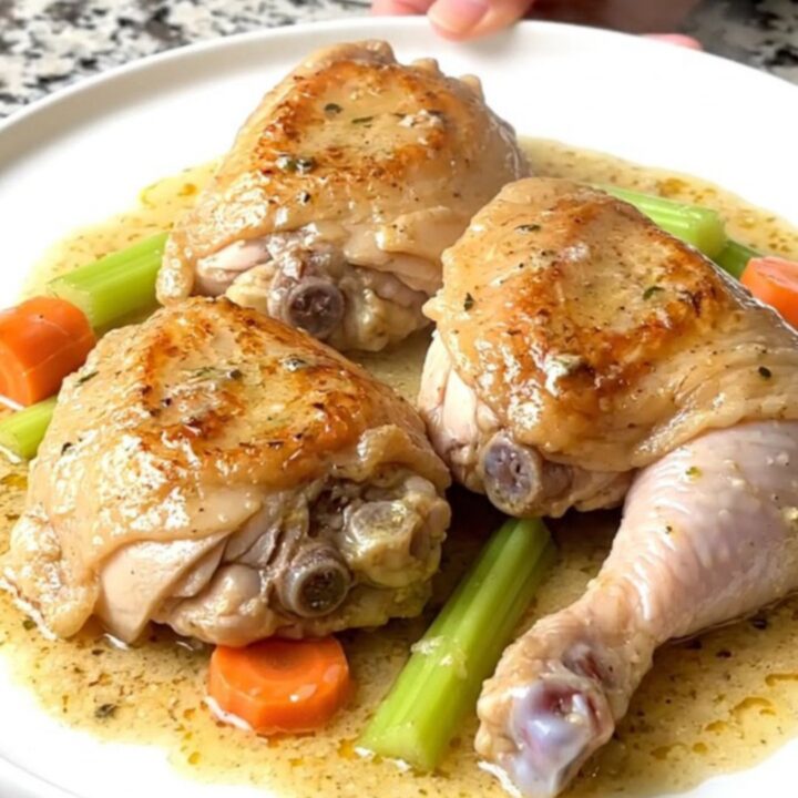 A close-up of a creamy chicken fricassee in a slow cooker with visible chicken thighs and carrots.